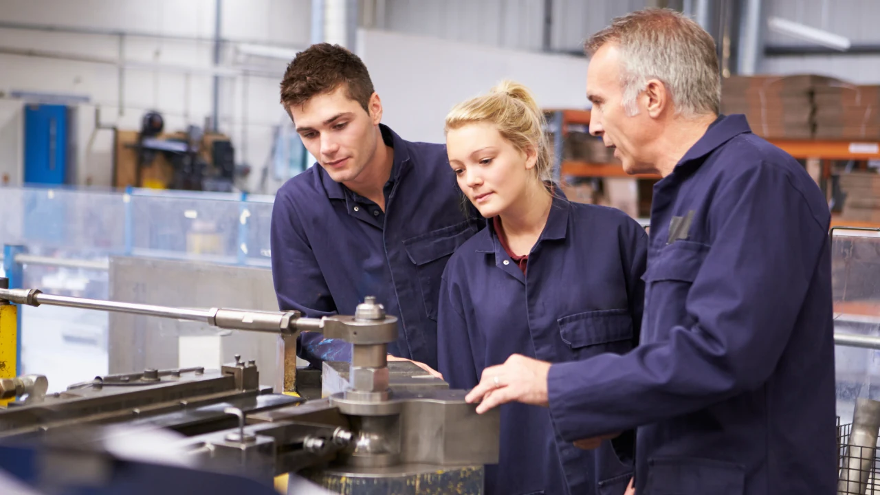 live-library-training Senior technician showing two younger technicians how to service a machine on the shop floor